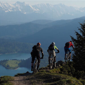 Tres cicilistas en mountain bike con la vista del Lago Meliquina debajo.